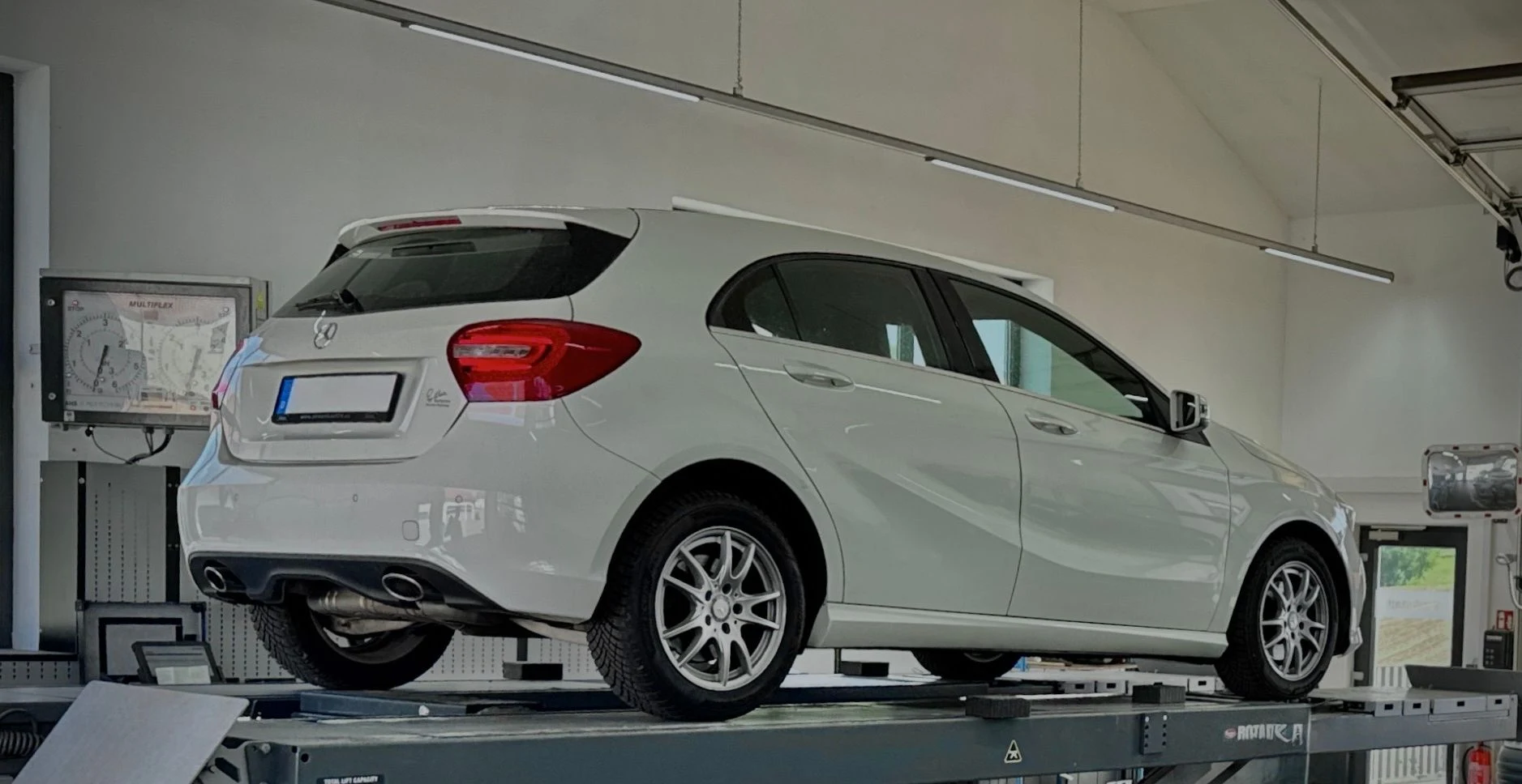 Weißer Mercedes A-Klasse auf der Hebebühne beim Bremsentest zur Hauptuntersuchung
